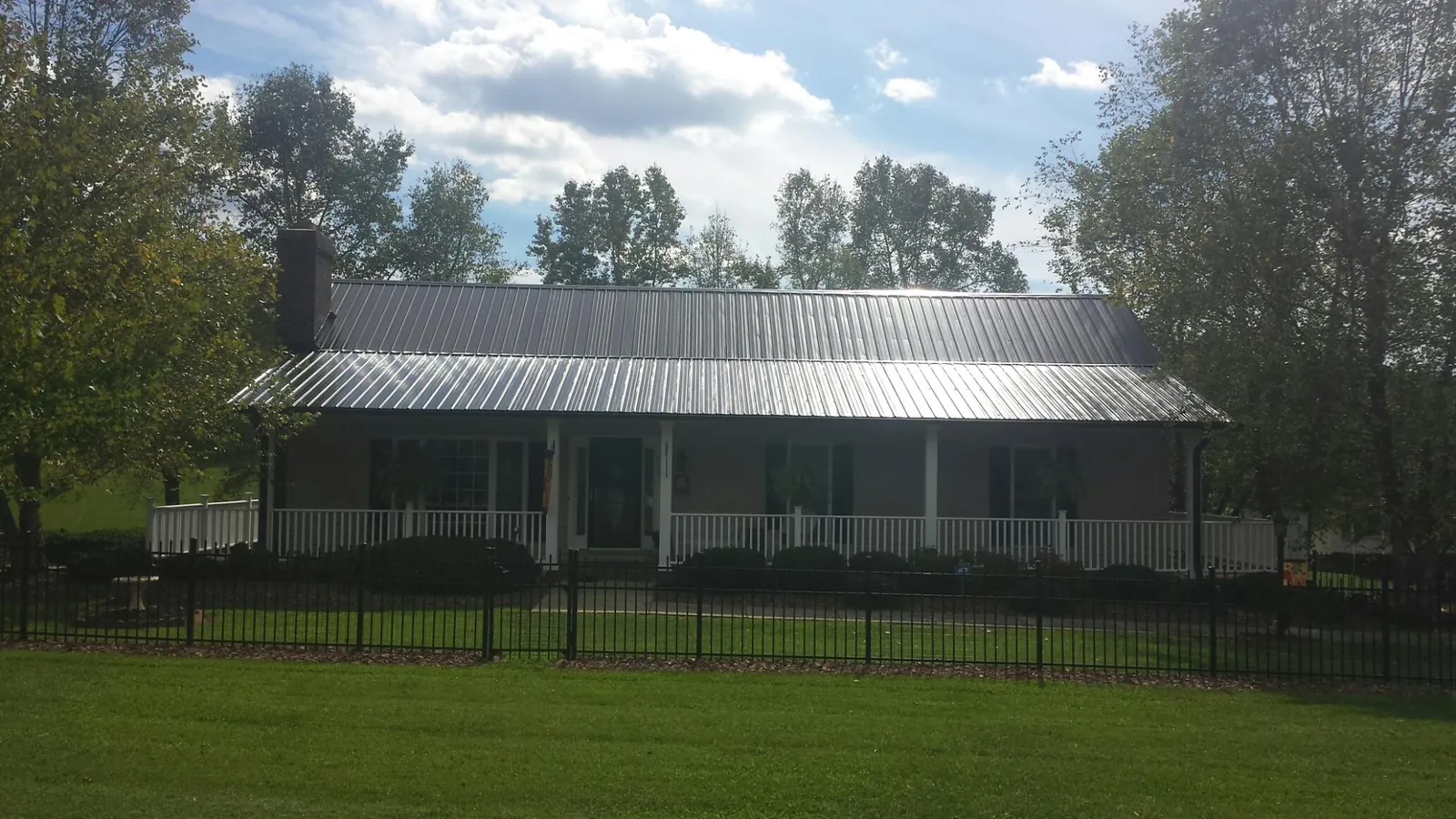 Gray metal roof on a brick ranch with a full width front porch — Gutter Guard Installation work by our crew in Northfield
