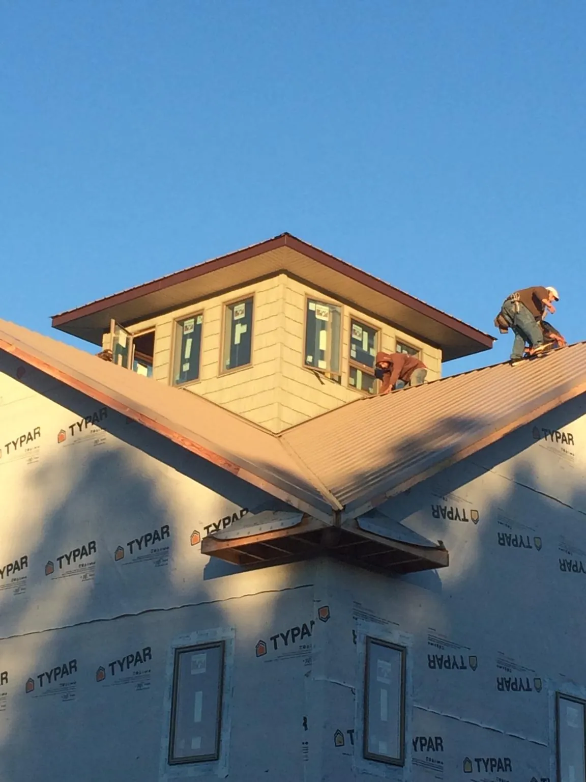 Roofers working around a rooftop cupola on a new metal roof at sunset — Roof Waterproofing in Northfield by Roofing Brothers